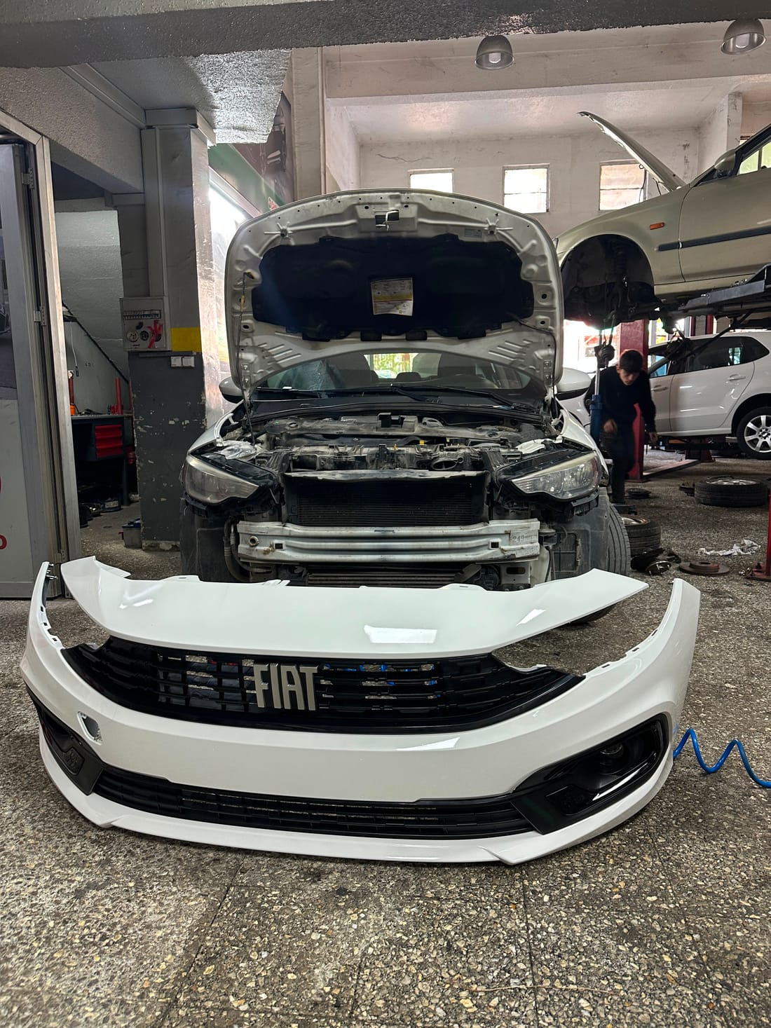 Tamponu sökülmüş Fiat Egea ve önünde aracın renginde boyanmış, ızgarası takılı yeni tampon — GMK Otomotiv Ankara